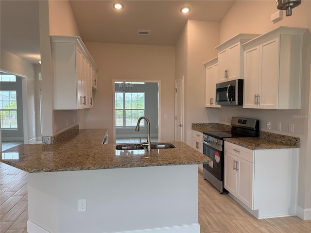 kitchen with visible vents, stainless steel appliances, stone counters, white cabinetry, and a sink