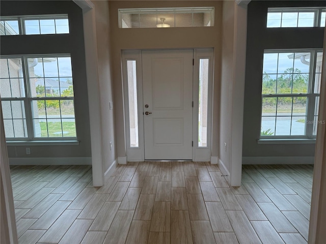 entryway with plenty of natural light, baseboards, and wood finish floors