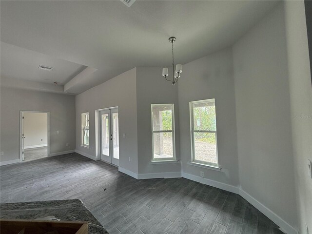 foyer entrance with dark wood-type flooring, french doors, a chandelier, a raised ceiling, and a towering ceiling