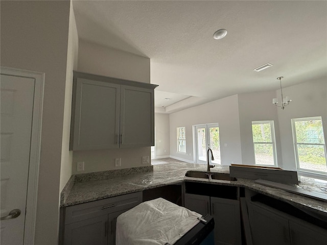 kitchen featuring dark stone counters, a wealth of natural light, sink, and gray cabinetry