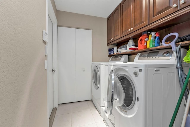 washroom featuring cabinets, light tile patterned floors, and washing machine and clothes dryer