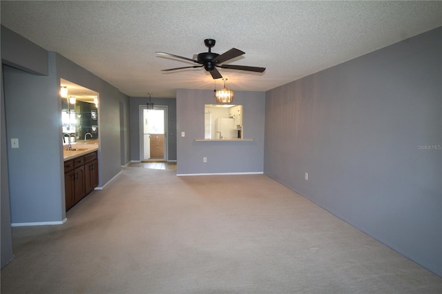 unfurnished living room with ceiling fan, light colored carpet, and a textured ceiling