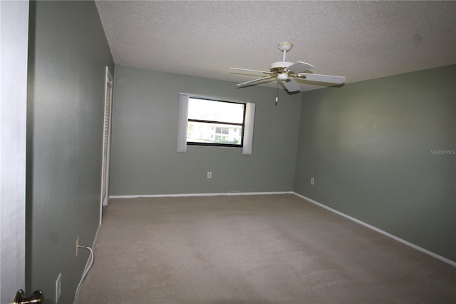 spare room with ceiling fan, a textured ceiling, and carpet