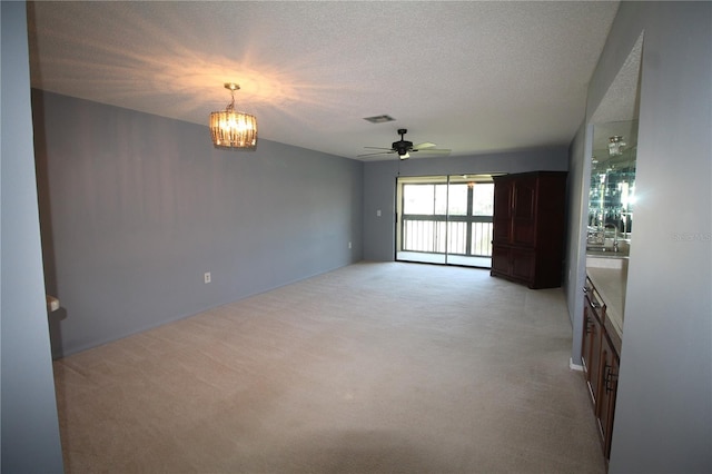 255 Mission Trl S Unit J, Venice, FL 34285 - unfurnished living room featuring ceiling fan with notable chandelier, visible vents, a textured ceiling, and light colored carpet