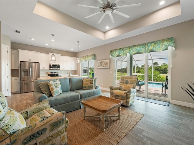 living room with light wood-type flooring, ceiling fan, and sink