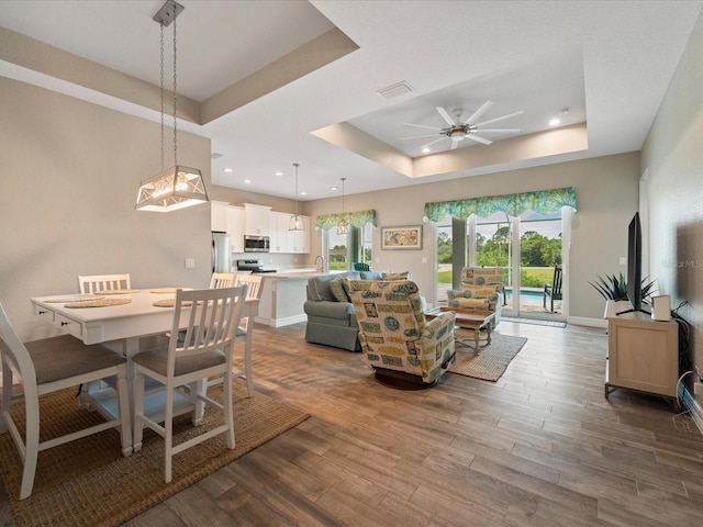 living room featuring a tray ceiling, hardwood / wood-style floors, and ceiling fan