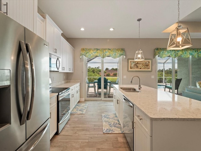 kitchen with sink, an island with sink, white cabinetry, hanging light fixtures, and appliances with stainless steel finishes