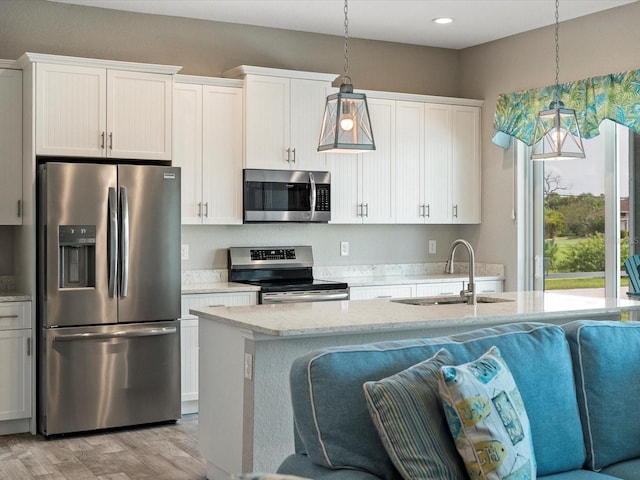 kitchen with appliances with stainless steel finishes, light hardwood / wood-style floors, white cabinetry, pendant lighting, and sink