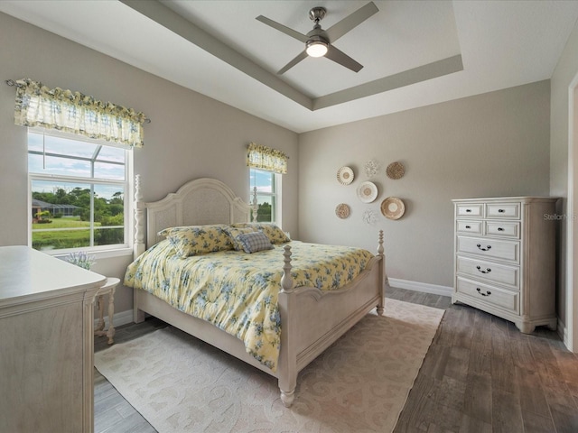 bedroom featuring wood-type flooring, ceiling fan, and a raised ceiling