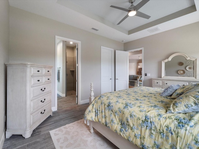 bedroom featuring ceiling fan, a raised ceiling, and dark hardwood / wood-style floors