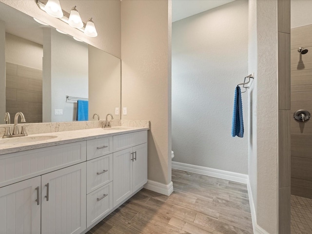 bathroom featuring a tile shower, wood-type flooring, vanity, and toilet