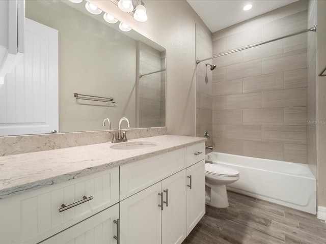 full bathroom with tiled shower / bath combo, vanity, toilet, and hardwood / wood-style flooring