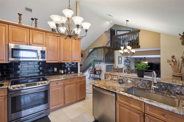 kitchen featuring appliances with stainless steel finishes, vaulted ceiling, light stone countertops, pendant lighting, and sink