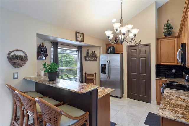 kitchen with pendant lighting, kitchen peninsula, backsplash, appliances with stainless steel finishes, and a kitchen breakfast bar