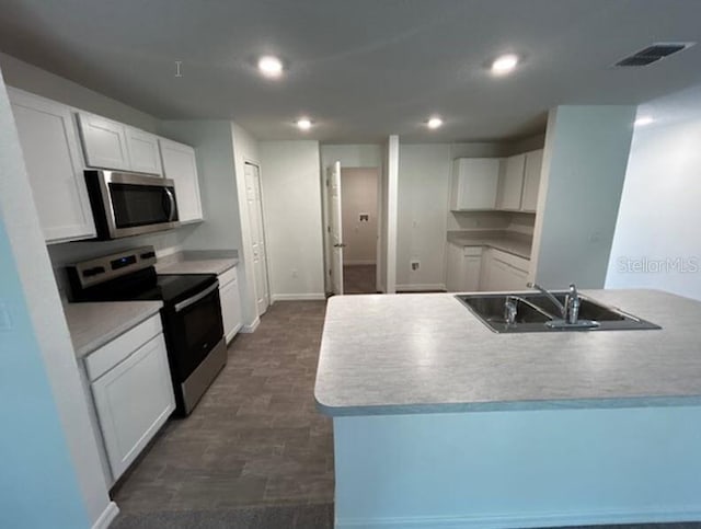 kitchen featuring appliances with stainless steel finishes, white cabinetry, and dark wood-type flooring