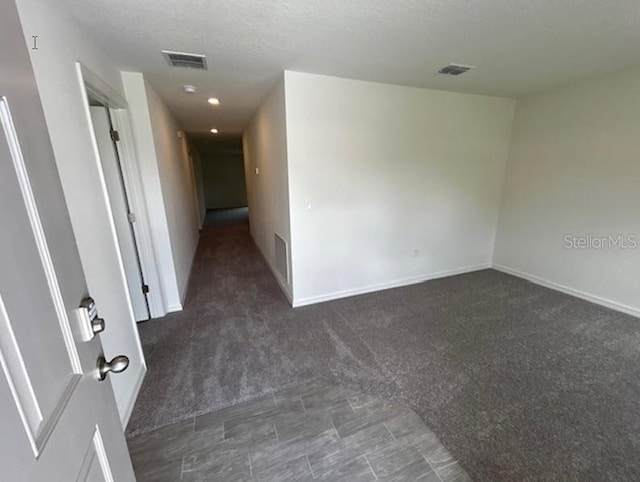 carpeted spare room featuring a textured ceiling