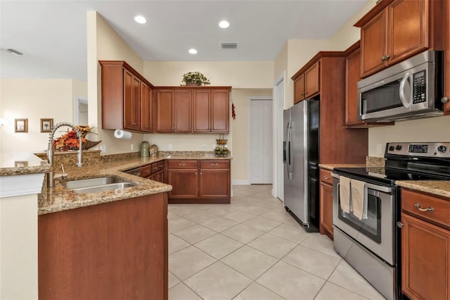 kitchen with appliances with stainless steel finishes, light tile patterned flooring, light stone counters, kitchen peninsula, and sink