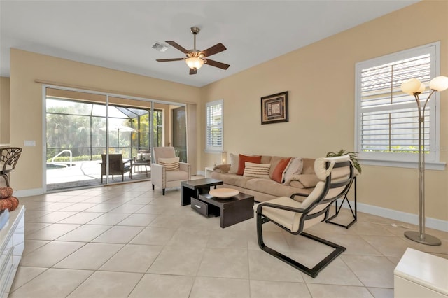 living area with light tile patterned floors, ceiling fan, visible vents, and baseboards