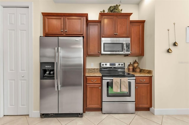 kitchen featuring appliances with stainless steel finishes, light tile patterned floors, and light stone counters