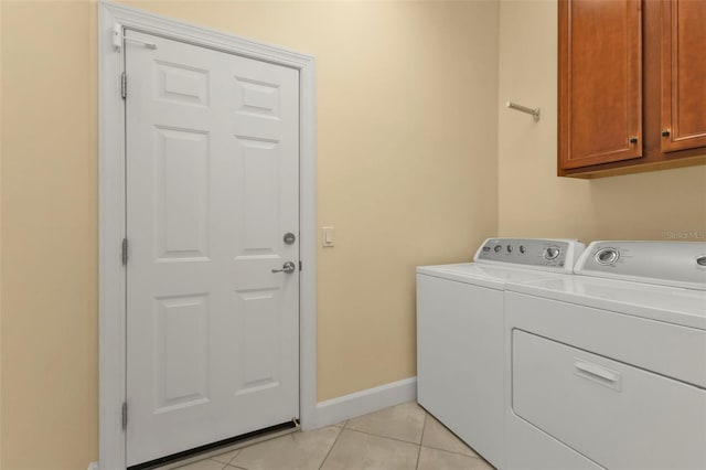 laundry room with cabinets, light tile patterned floors, and washing machine and clothes dryer