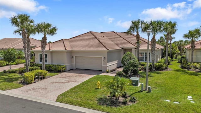 mediterranean / spanish-style home featuring an attached garage, a tiled roof, decorative driveway, stucco siding, and a front lawn