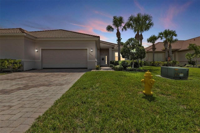 view of front of house with a garage, stucco siding, decorative driveway, and a yard