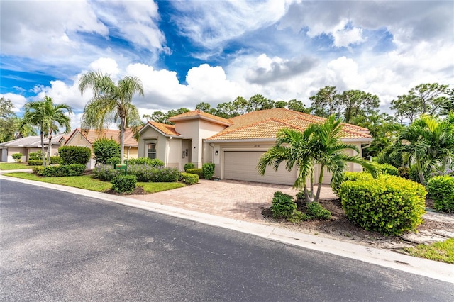 mediterranean / spanish-style house featuring stucco siding, driveway, a tiled roof, and a garage