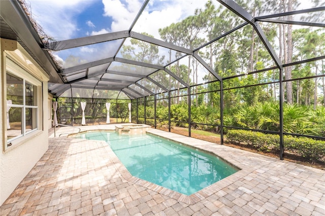 view of pool featuring glass enclosure, a pool with connected hot tub, and a patio