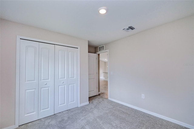 unfurnished bedroom featuring light carpet and a closet