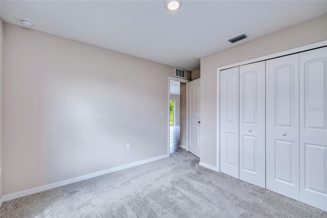 unfurnished bedroom with light colored carpet and a closet