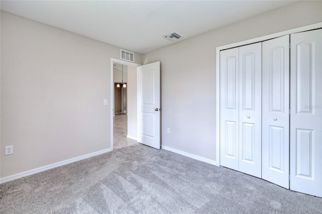 unfurnished bedroom featuring light carpet and a closet