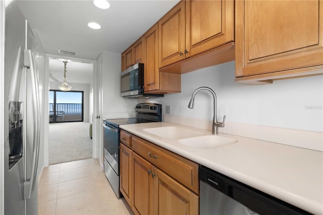 kitchen with appliances with stainless steel finishes, sink, light tile patterned floors, and decorative light fixtures