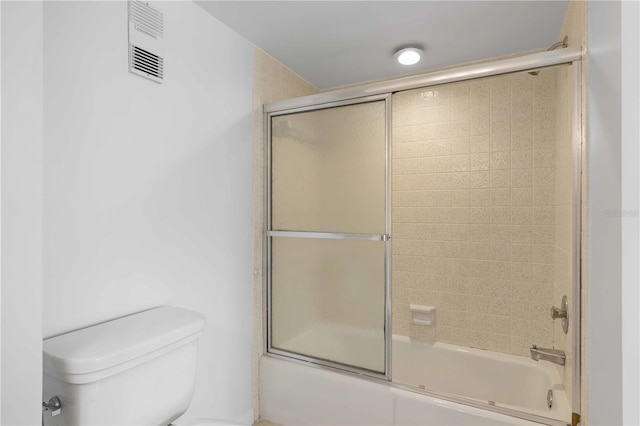 bathroom featuring bath / shower combo with glass door and toilet