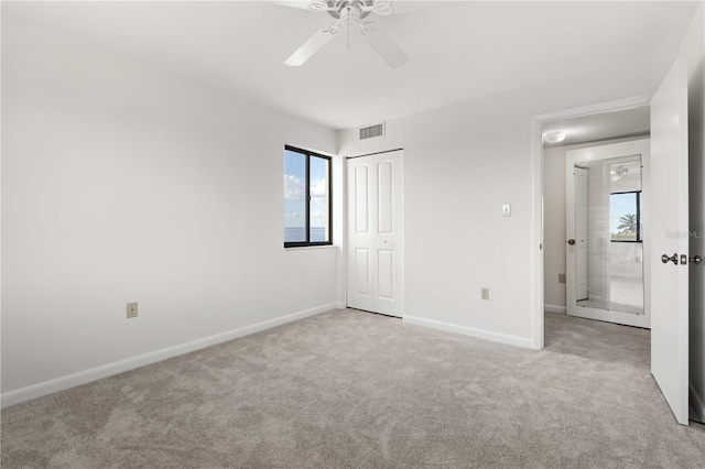 unfurnished bedroom with ceiling fan, a closet, and light carpet