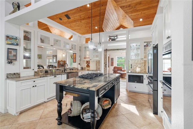 kitchen with hanging light fixtures, white cabinets, kitchen peninsula, light stone countertops, and wooden ceiling