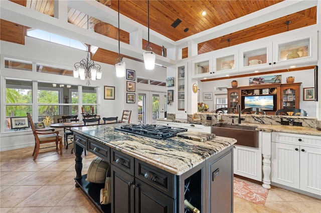 kitchen with white cabinetry, a kitchen island, light stone countertops, decorative light fixtures, and gas cooktop