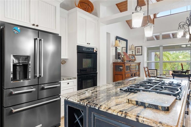 kitchen with white cabinets, stainless steel appliances, vaulted ceiling with beams, light stone countertops, and blue cabinets