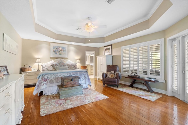 bedroom featuring light wood-type flooring, a tray ceiling, and ceiling fan