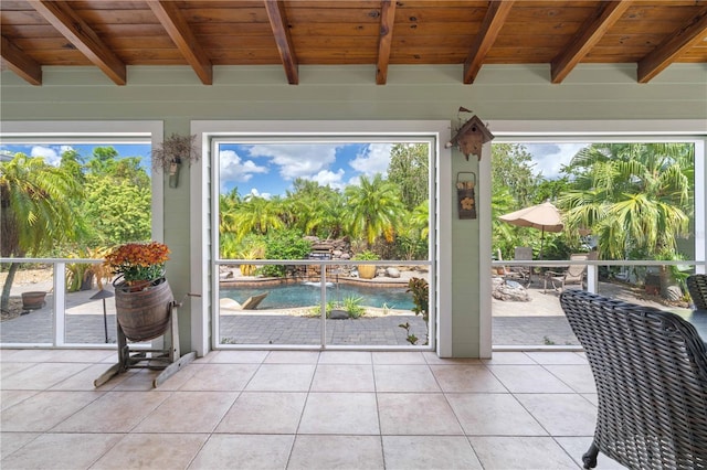 doorway to outside with a healthy amount of sunlight, wood ceiling, beam ceiling, and tile patterned flooring