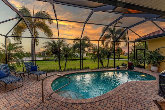 pool at dusk with a patio and glass enclosure