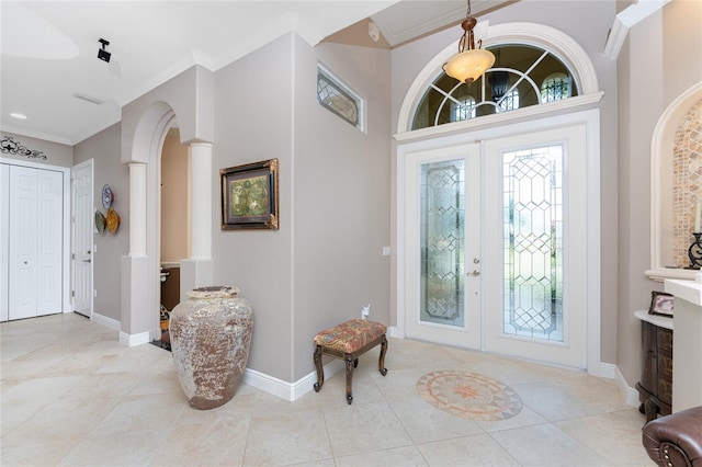 tiled foyer featuring ornate columns, a wealth of natural light, french doors, and ornamental molding