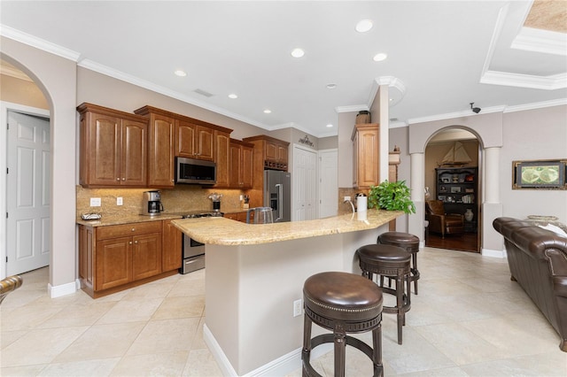 kitchen with backsplash, ornamental molding, appliances with stainless steel finishes, kitchen peninsula, and a breakfast bar area