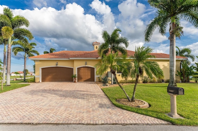 mediterranean / spanish-style home featuring a front yard and a garage