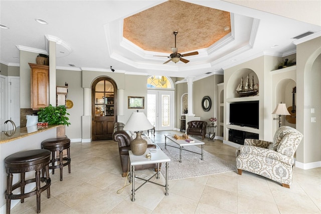 tiled living room with french doors, crown molding, built in shelves, ceiling fan, and a tray ceiling