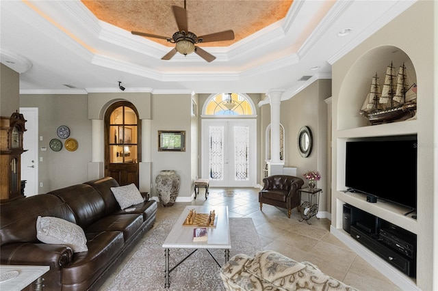 living room with a raised ceiling, ceiling fan, crown molding, light tile patterned floors, and built in features