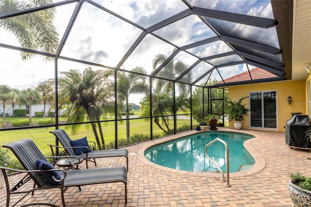 view of swimming pool with a yard, glass enclosure, and a patio area