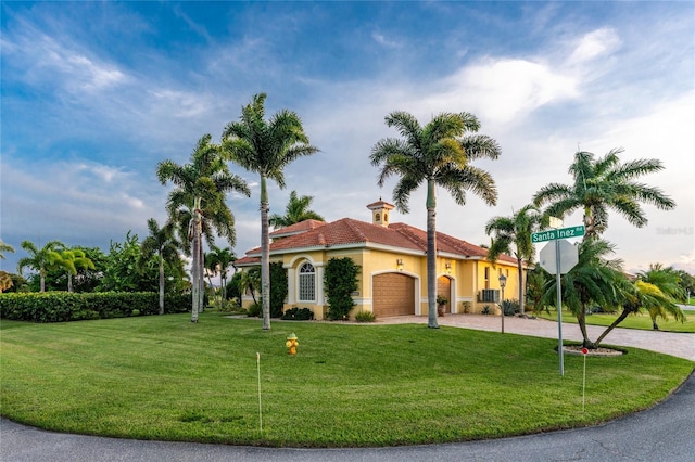 mediterranean / spanish home with cooling unit, a garage, and a front lawn