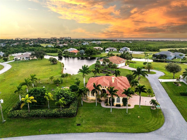 aerial view at dusk featuring a water view