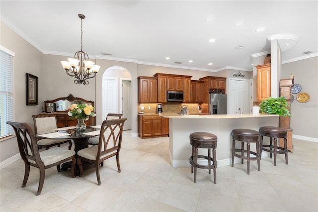 kitchen featuring a breakfast bar, pendant lighting, tasteful backsplash, stainless steel appliances, and an inviting chandelier