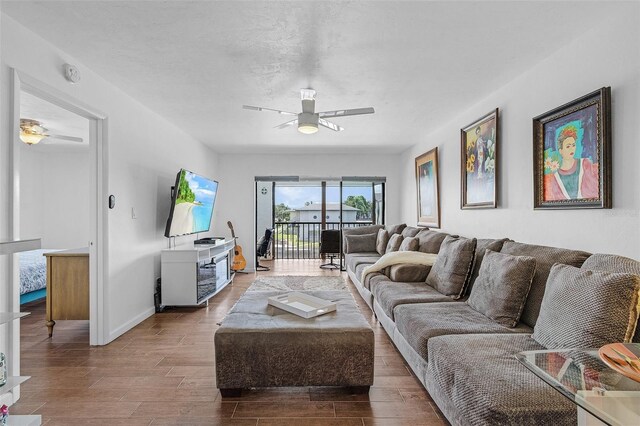 living room with a ceiling fan, baseboards, and wood finished floors